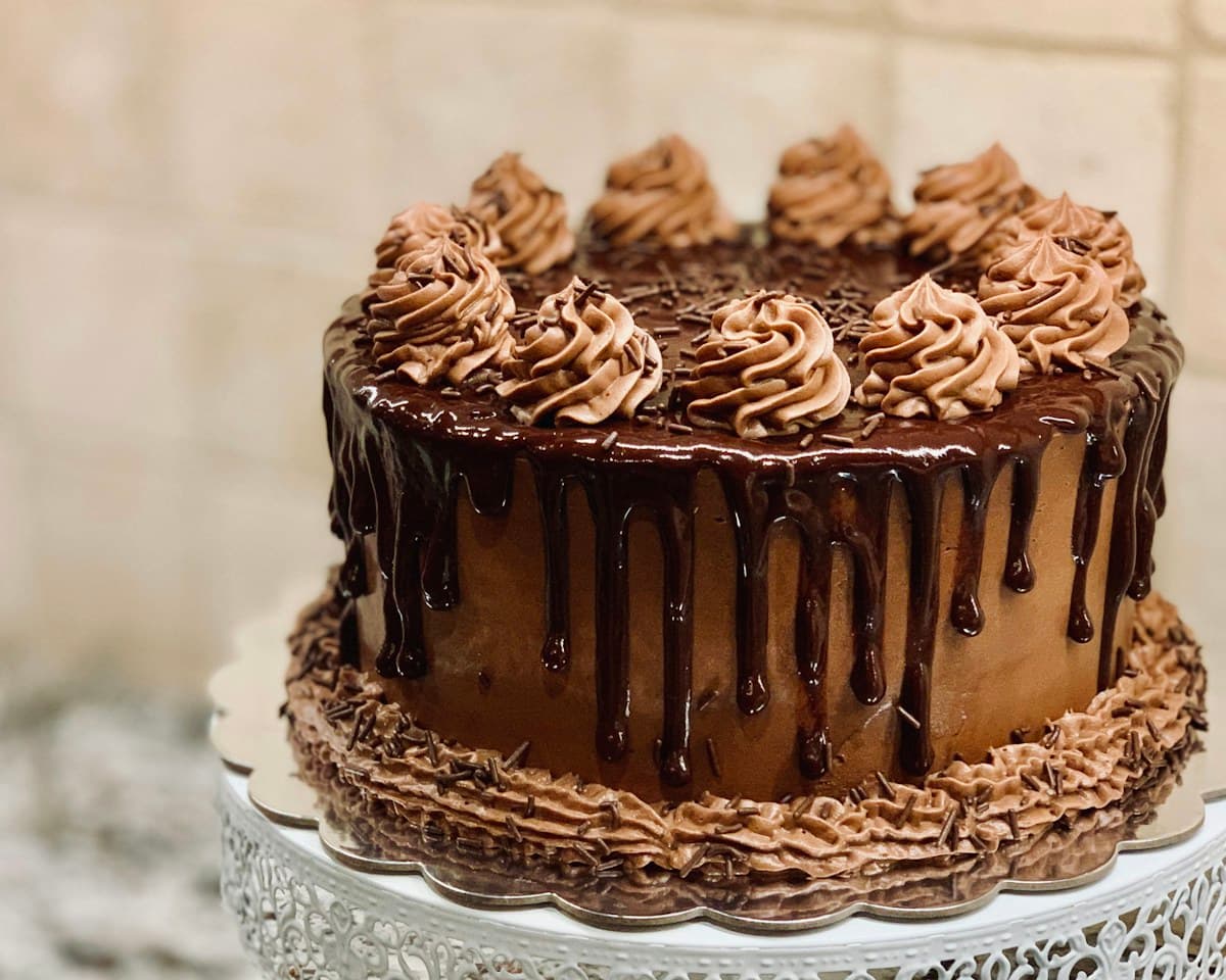 Torta de chocolate entera, bañada en chocolate y decorada con rosetas de crema